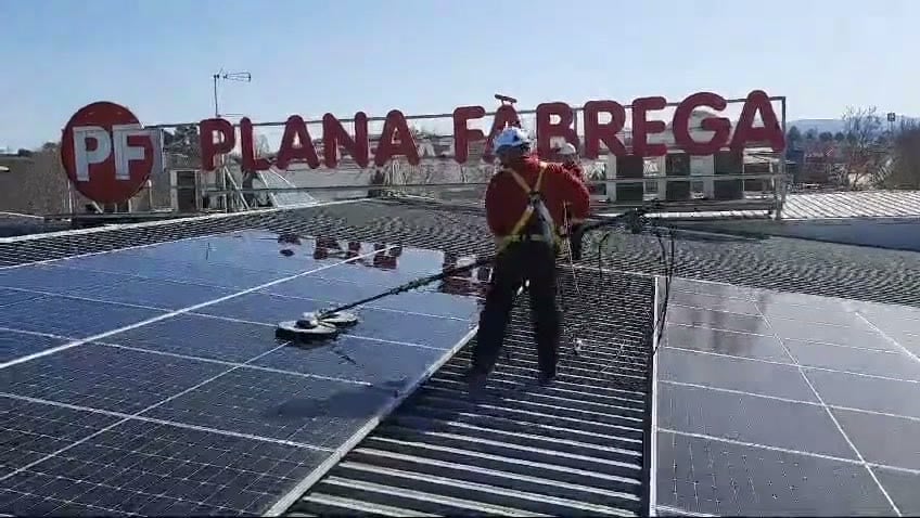Trabajador de Plana Fàbrega limpiando paneles solares en tejado